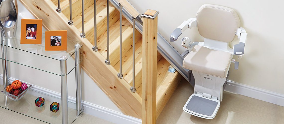 A stairlift installed beside a wooden staircase in a home.
