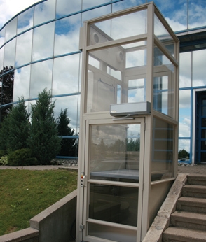 Outdoor elevator installed next to a staircase for accessibility at a modern building.