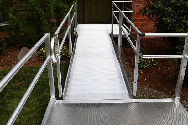 Aluminum ramp with handrails leading to a door.