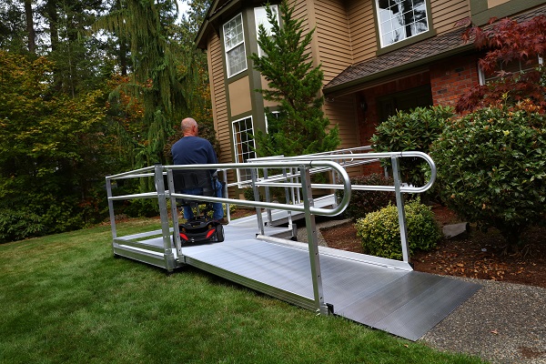 A person in a wheelchair using a ramp to access a residential building.