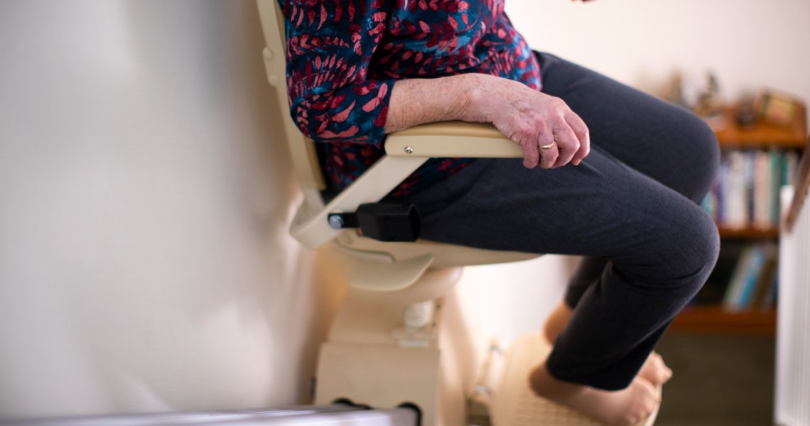 A person using a stairlift to ascend or descend stairs indoors.