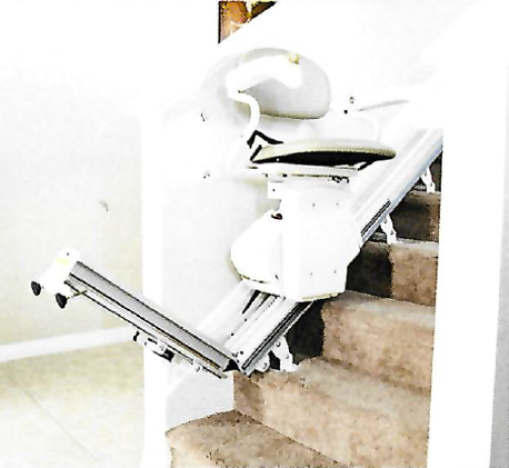 Stairlift installed on a staircase, chair located at the bottom of the stairs.