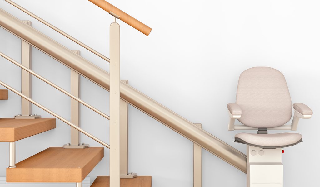 A stairlift installed beside a wooden staircase with a beige seat.