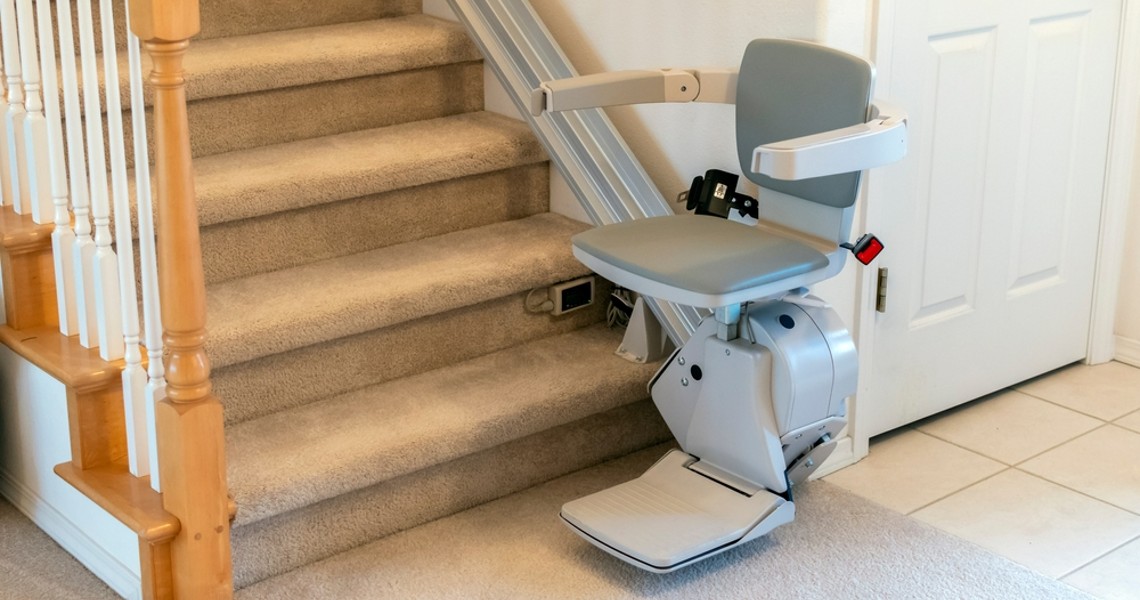 A stairlift was installed beside a staircase and a white door.