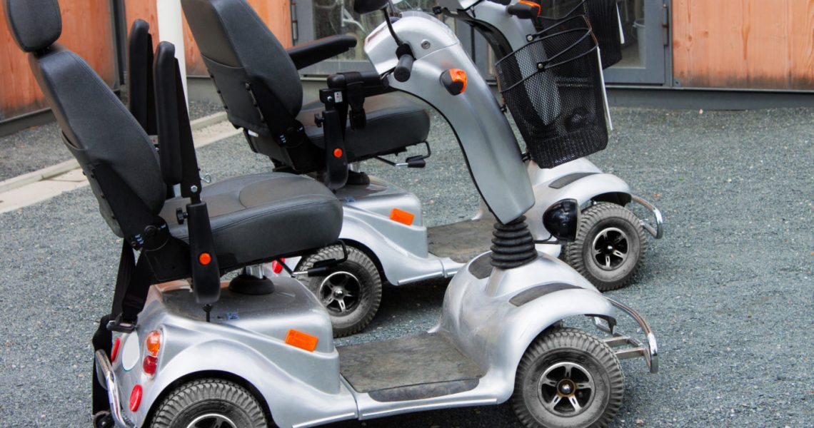 Two mobility scooters parked side by side.